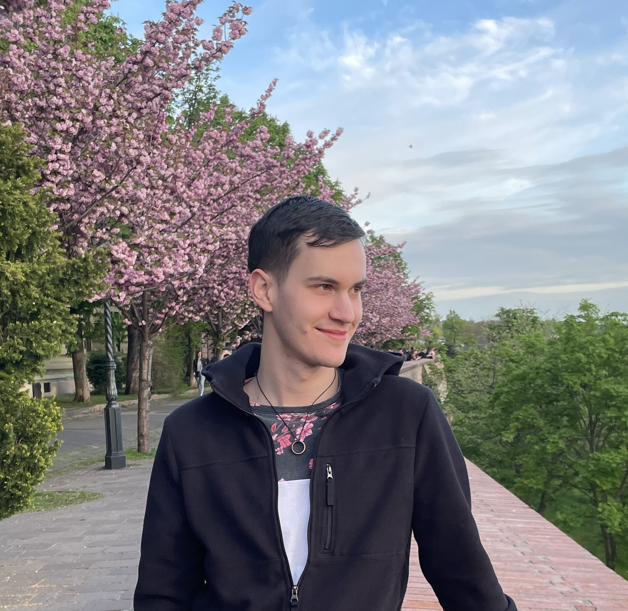 Mark standing in front of blossoming trees, looking to the right